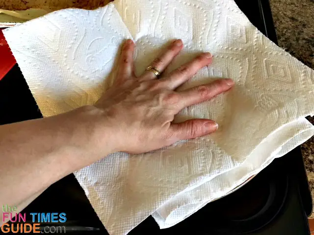 Press down on the paper towels to soak up grease from the cooked bacon.