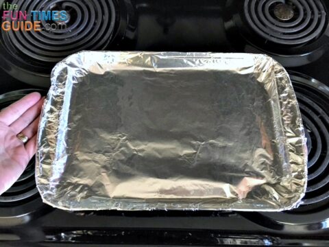 When cooking bacon in the oven, you first need to line a rimmed cookie sheet with aluminum foil.